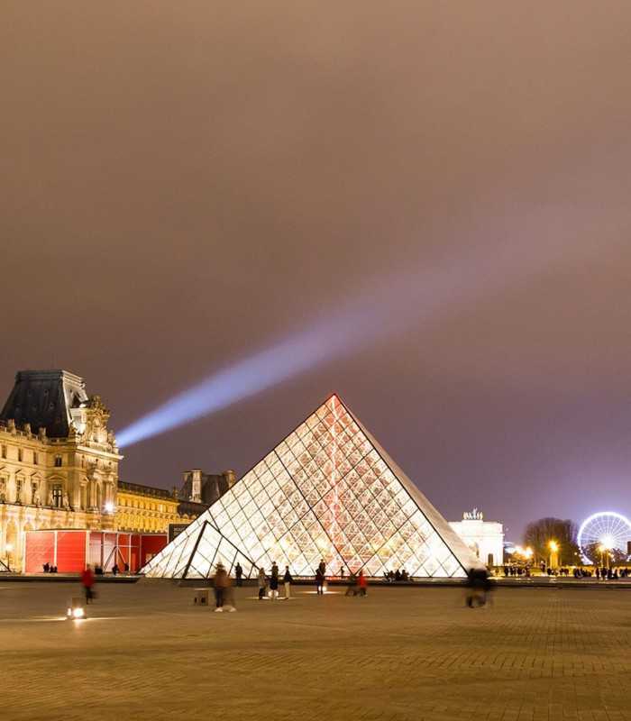 Night view of the Louvre Pyramid glowing in the Paris evening sky