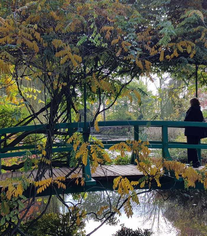Visitor reflecting alone on Monet’s Japanese Bridge in Giverny, France, during a private guided tour from Paris
