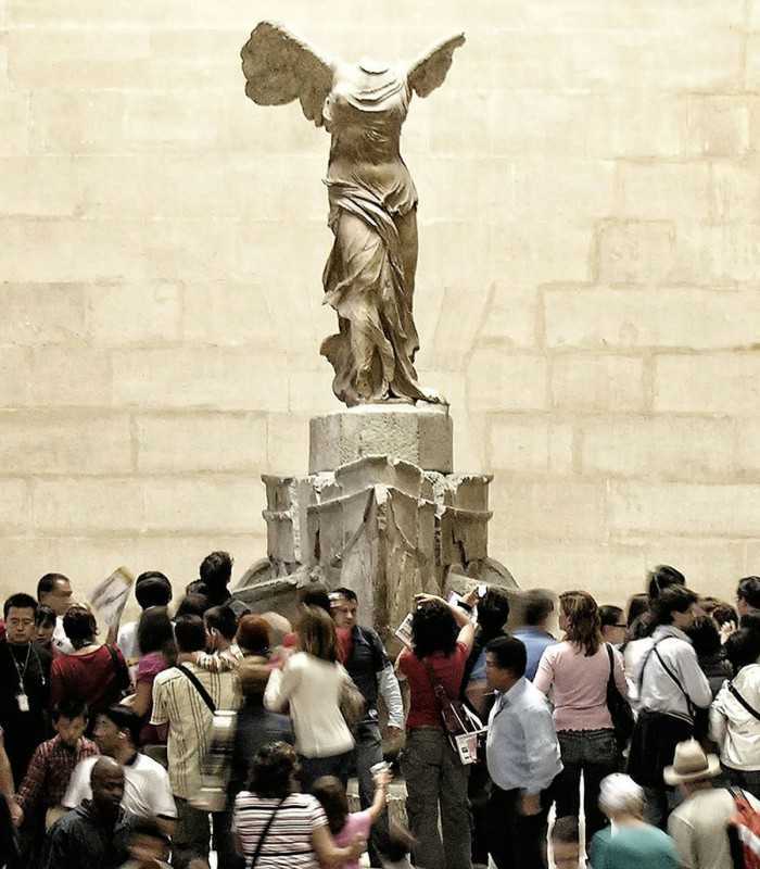 Private cultural tour of the Louvre Museum with a guide explaining the historic Winged Victory of Samothrace statue.